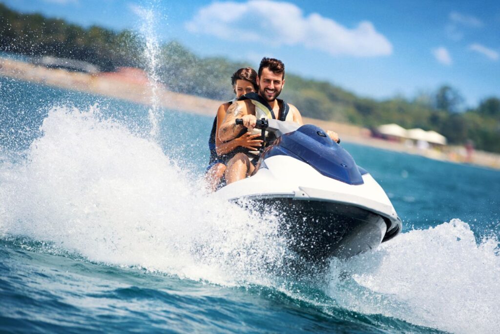 A man and woman riding a jet ski in the ocean.